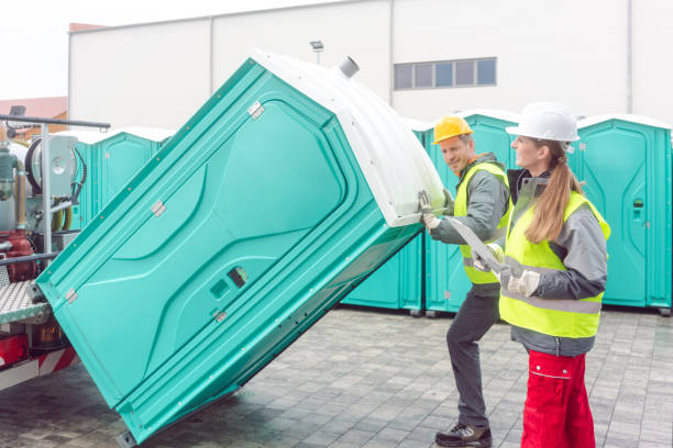 Worker loading portable toilets on truck for delivery